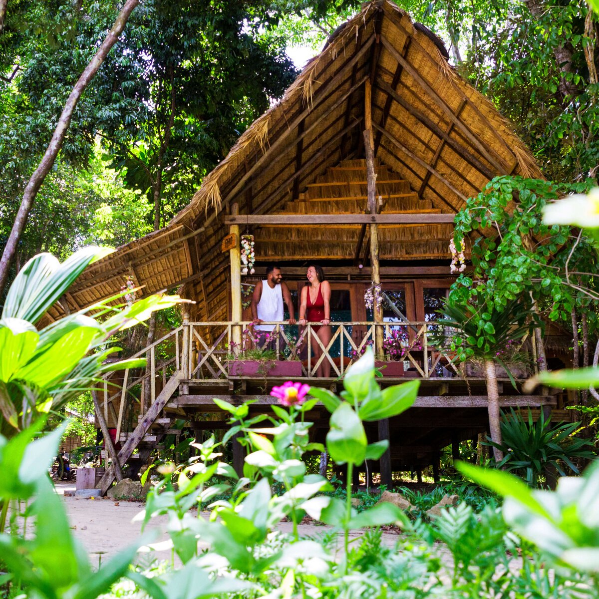 Couple standing on balcony of treehouse accommodation in the jungle